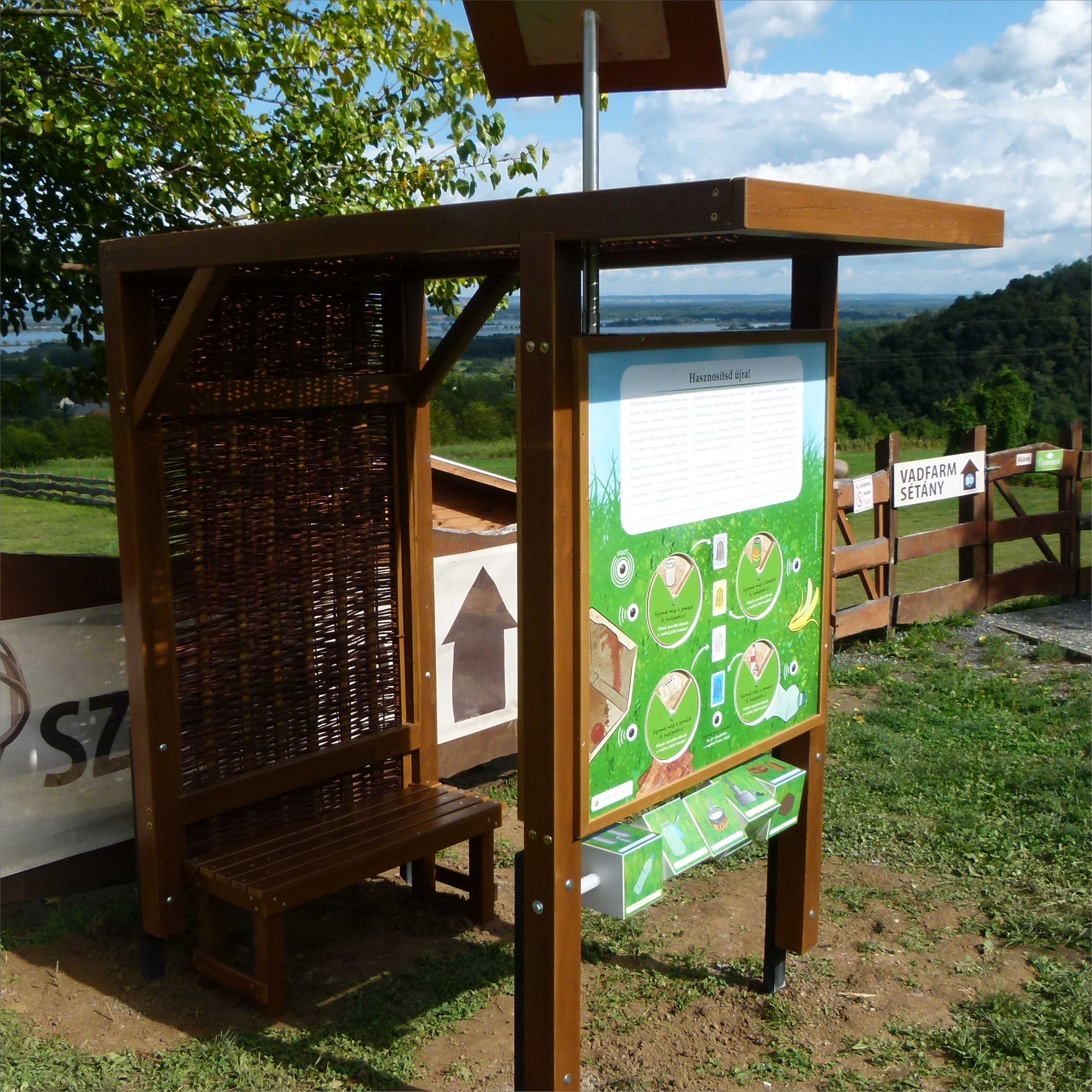 Interaktív pihenőhely vesszőfonattal, paddal és két játékos tanösvénytáblával.